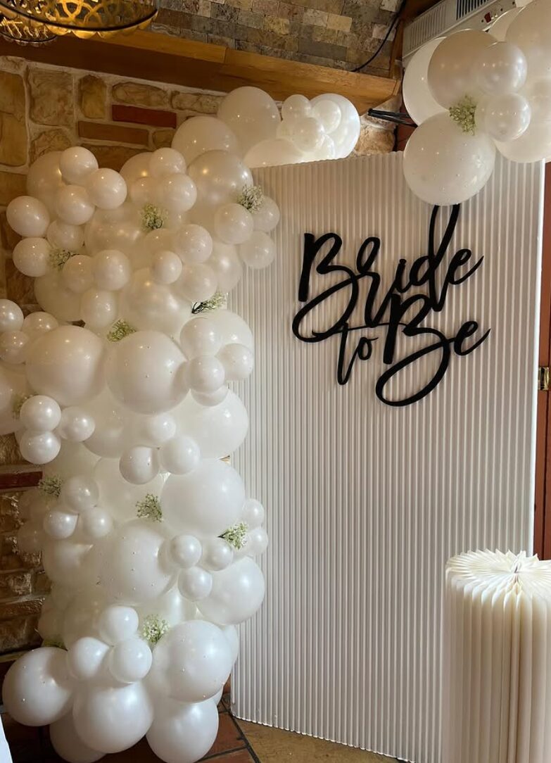 White balloon installation beside a fluted backdrop with a Bride To Be sign