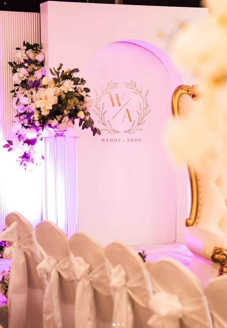 Blush wedding backdrop with gold monogram, floral arrangements and draped chair styling