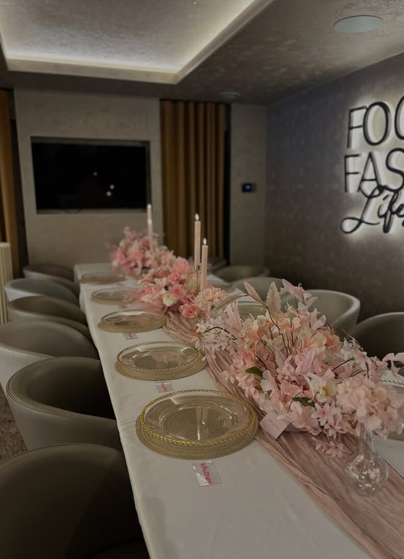 Long banquet table styled with blush florals, glass charger plates and taper candles